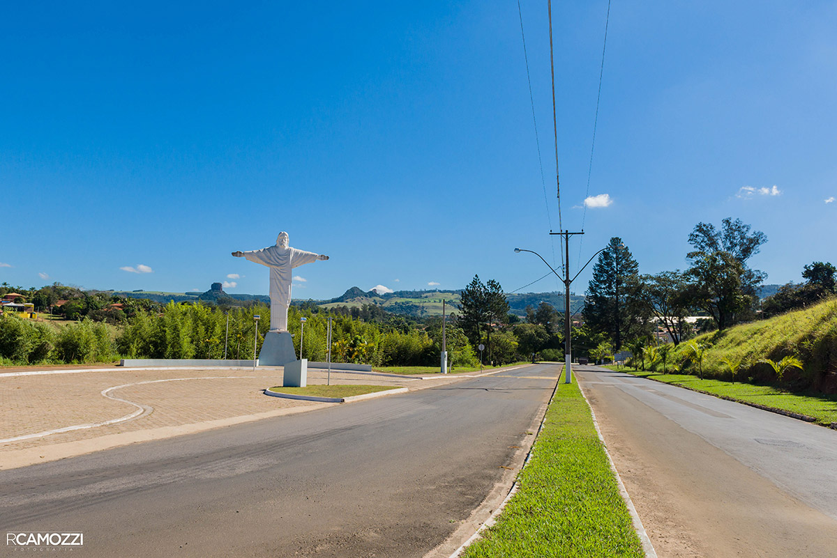 Estátua do Cristo na entrada de Analândia (SP), com o Morro do Cuscuzeiro e o Morro do Camelo ao fundo sob céu azul