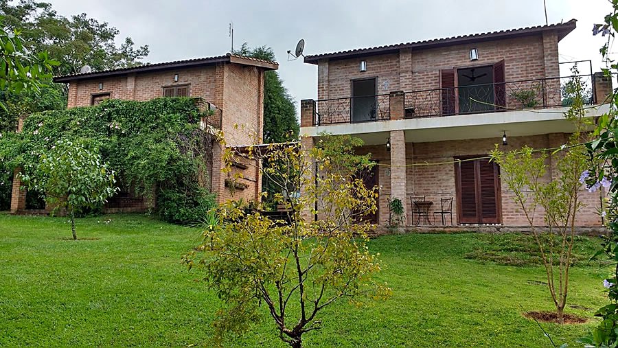 Construções de tijolo do Chalé Macaúva em Analândia (SP), cercadas de gramado e árvores