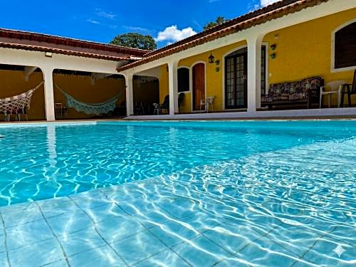 Piscina e varanda com redes da Pousada Casa Amarela em Analândia (SP), casa amarela de telhado de telha