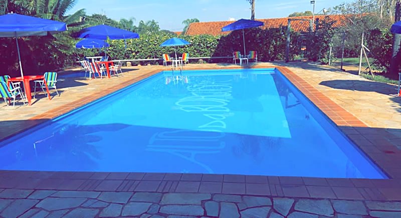 Piscina do Hotel Alto da Boa Vista em Analândia (SP), com guarda-sóis azuis e cadeiras ao redor